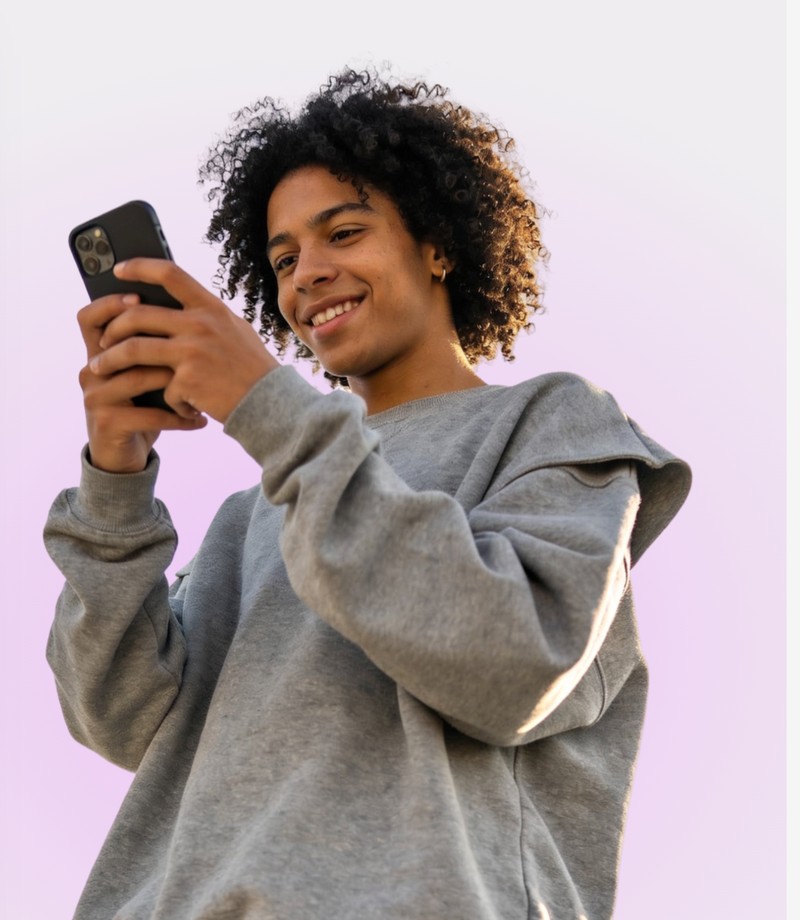 Homem jovem sorrindo enquanto usa o celular